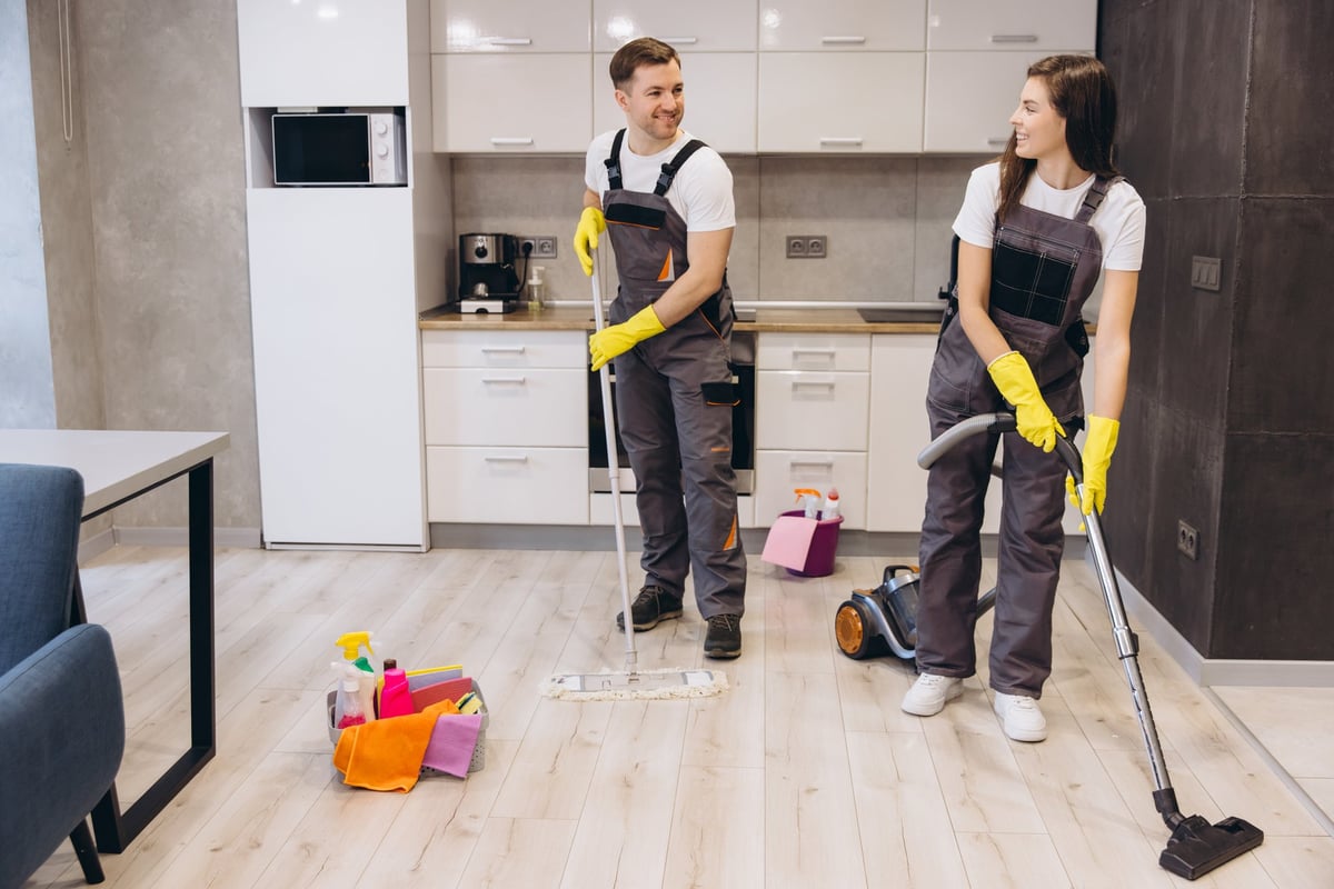 Equipo de limpieza trabajando en un apartamento moderno entre estancias